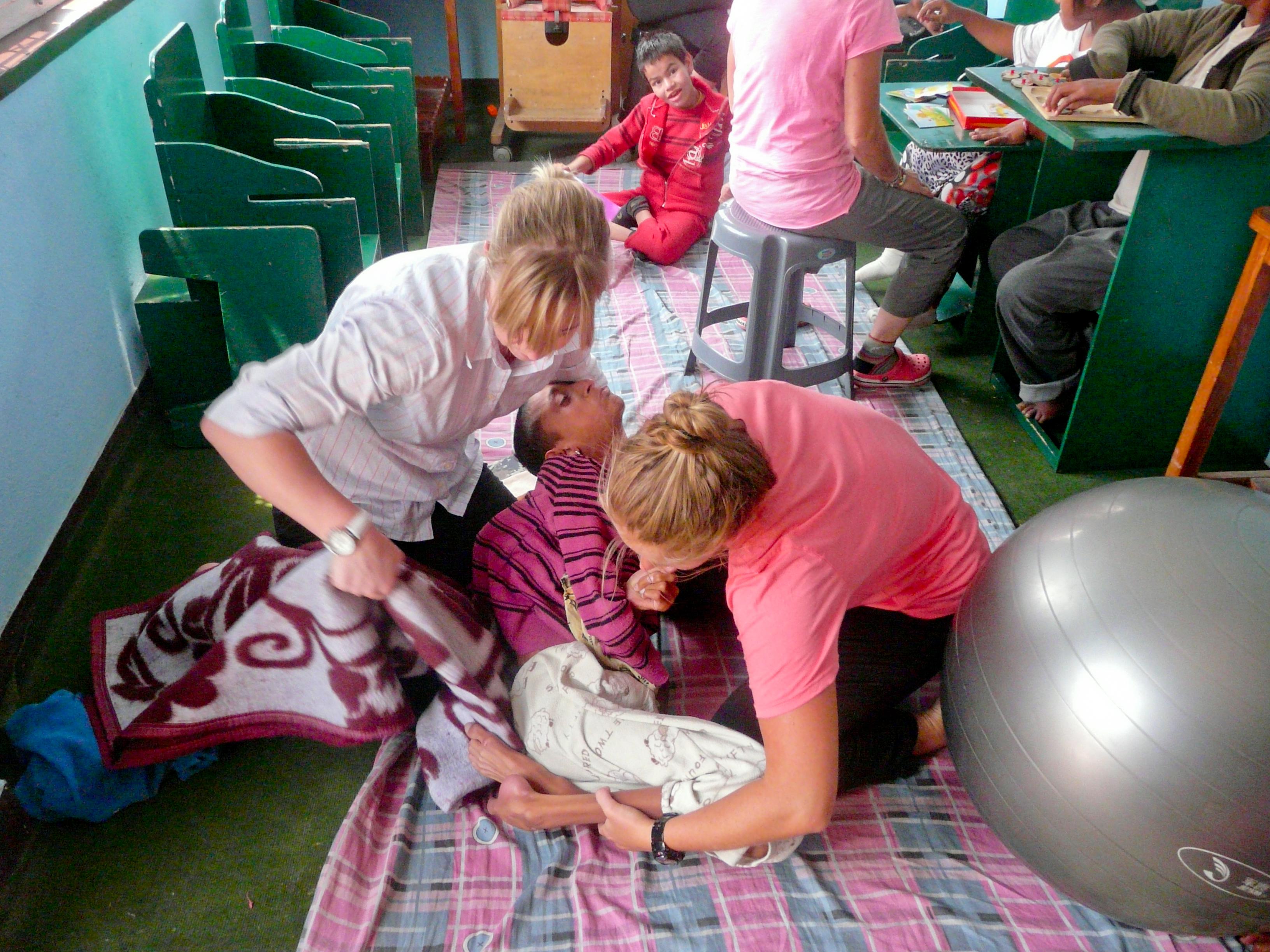 Una mujer local ejercitándose durante su sesión de fisioterapia. Internas de Fisioterapia en Nepal ayudan a una mujer discapacitada a ejercitar sus piernas.